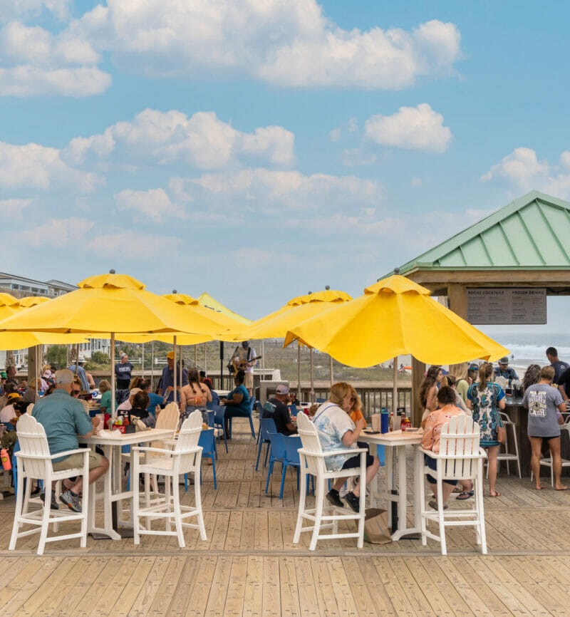 a group of people sitting at tables under yellow umbrellas