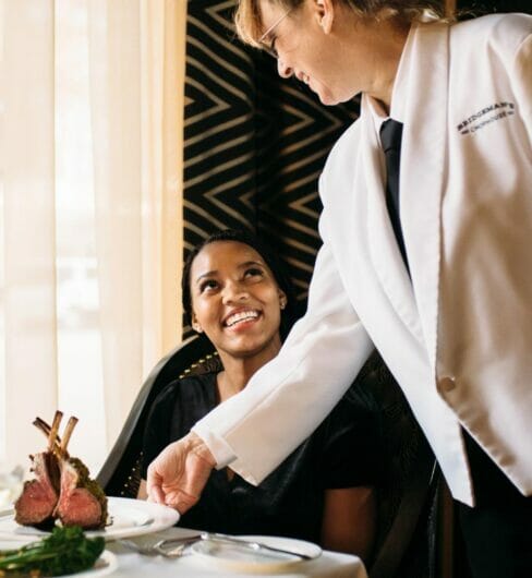 server delivering dish to seated dining guest