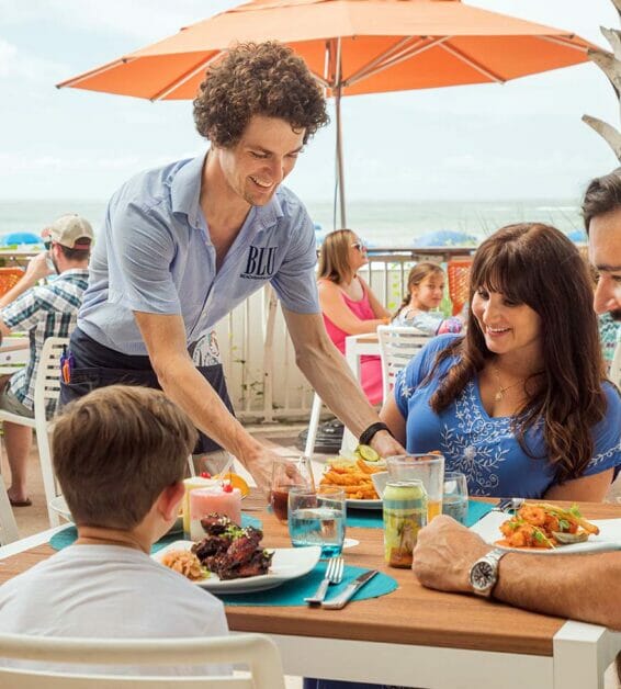man serving dining family at outdoor restaurant
