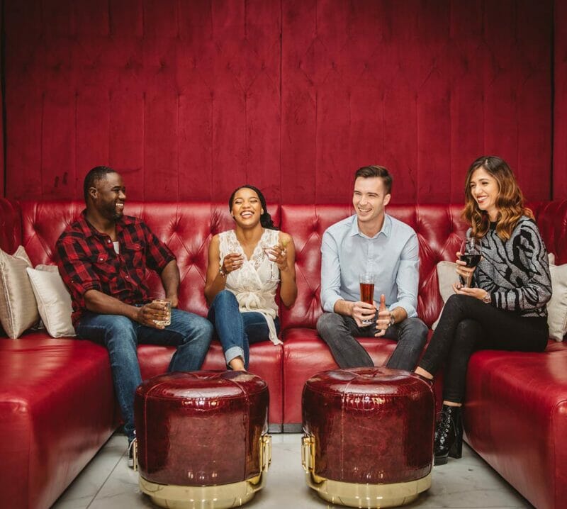 four friends sitting in bar lounge seating smiling